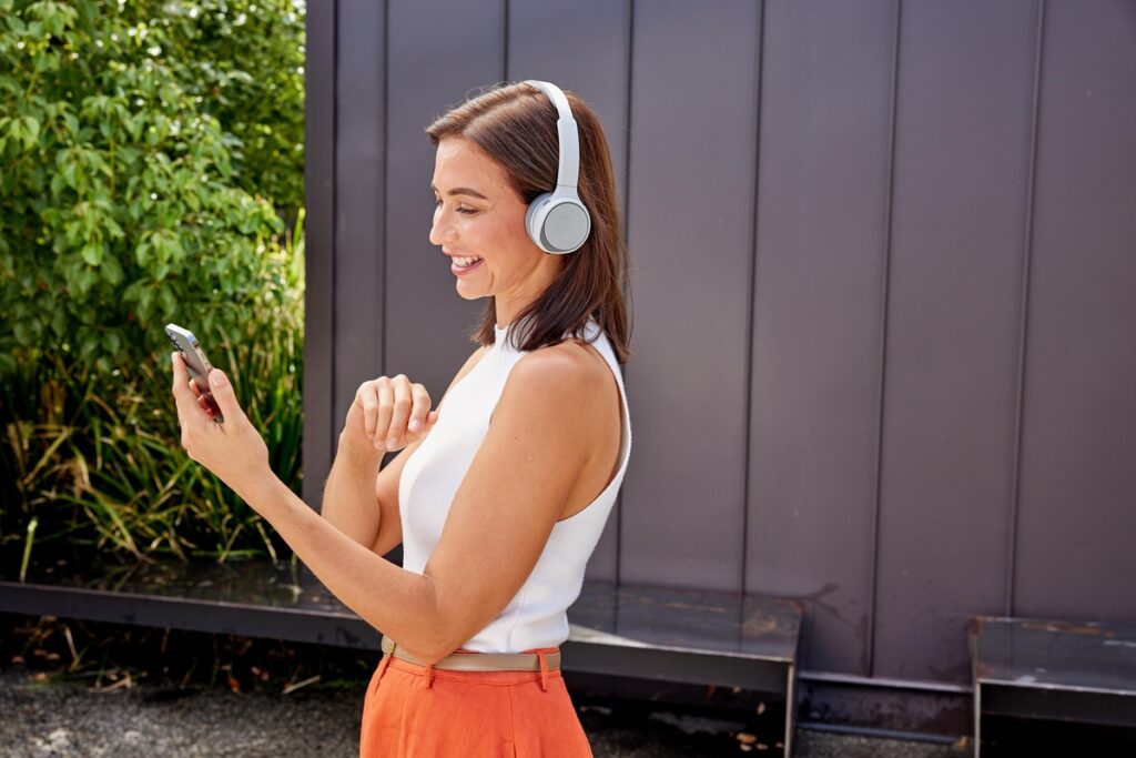 Femme souriante communiquant sur son smartphone et un casque Bang et Olufsen Cisco de qualité HD